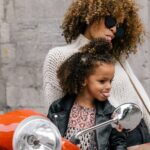 woman and girl showing their tongues beside motorcycle